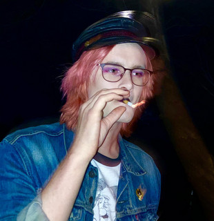 Quinn Decker smoking a cigarette with pink hair and a hat